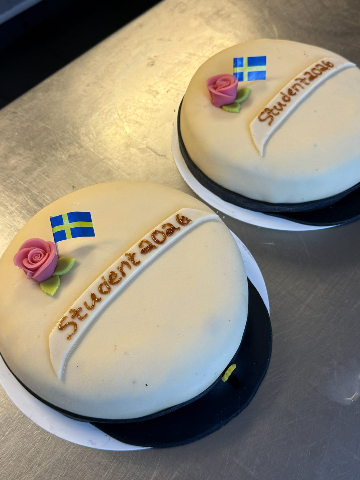 Två studenttårtor med texten Student 2026, svensk flagga och sockerros